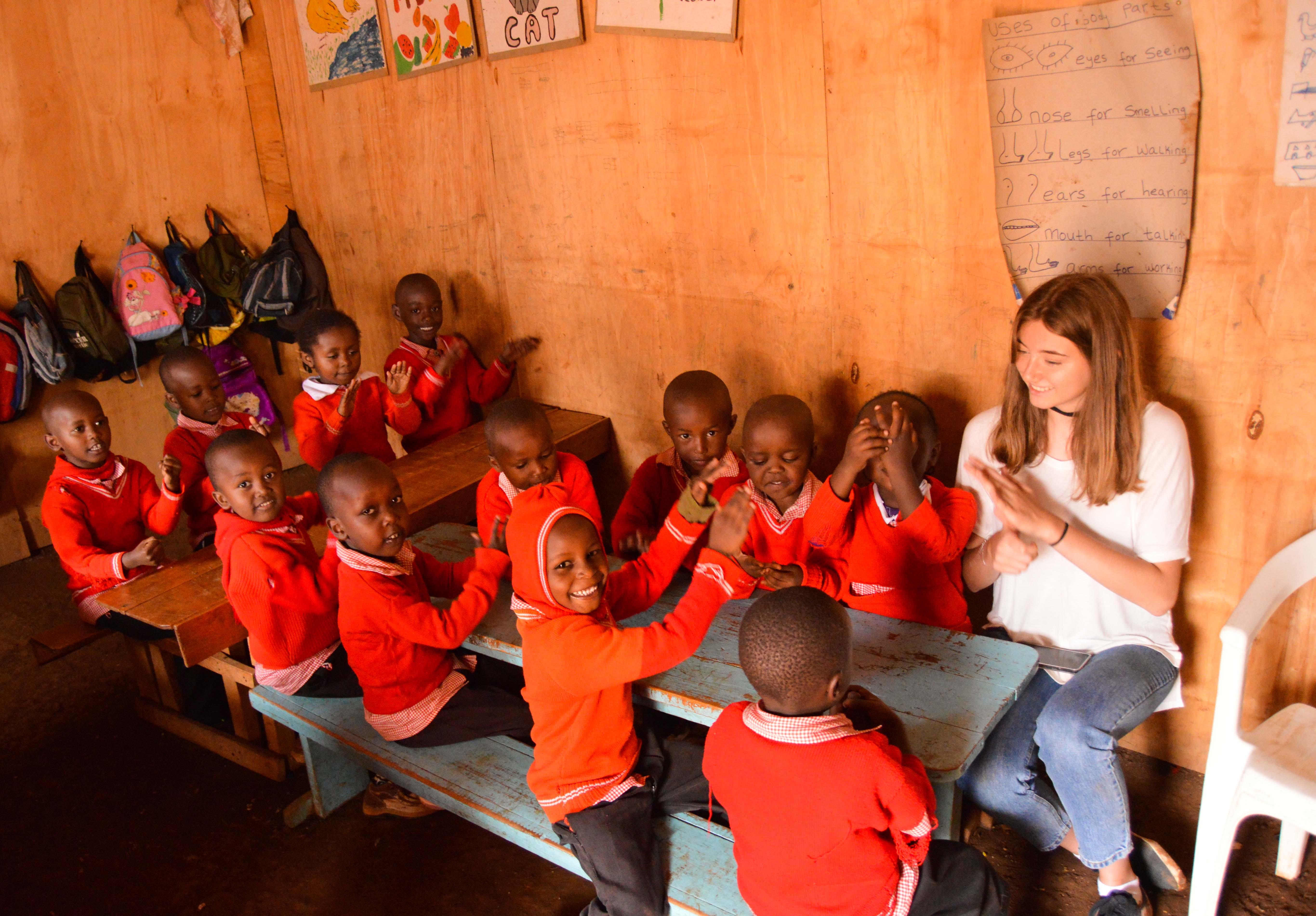 Niños aplaudiendo en actividad con voluntaria social en Kenia. Voluntaria realiza actividad didáctica con niños en preescolar de su voluntariado social en Kenia.